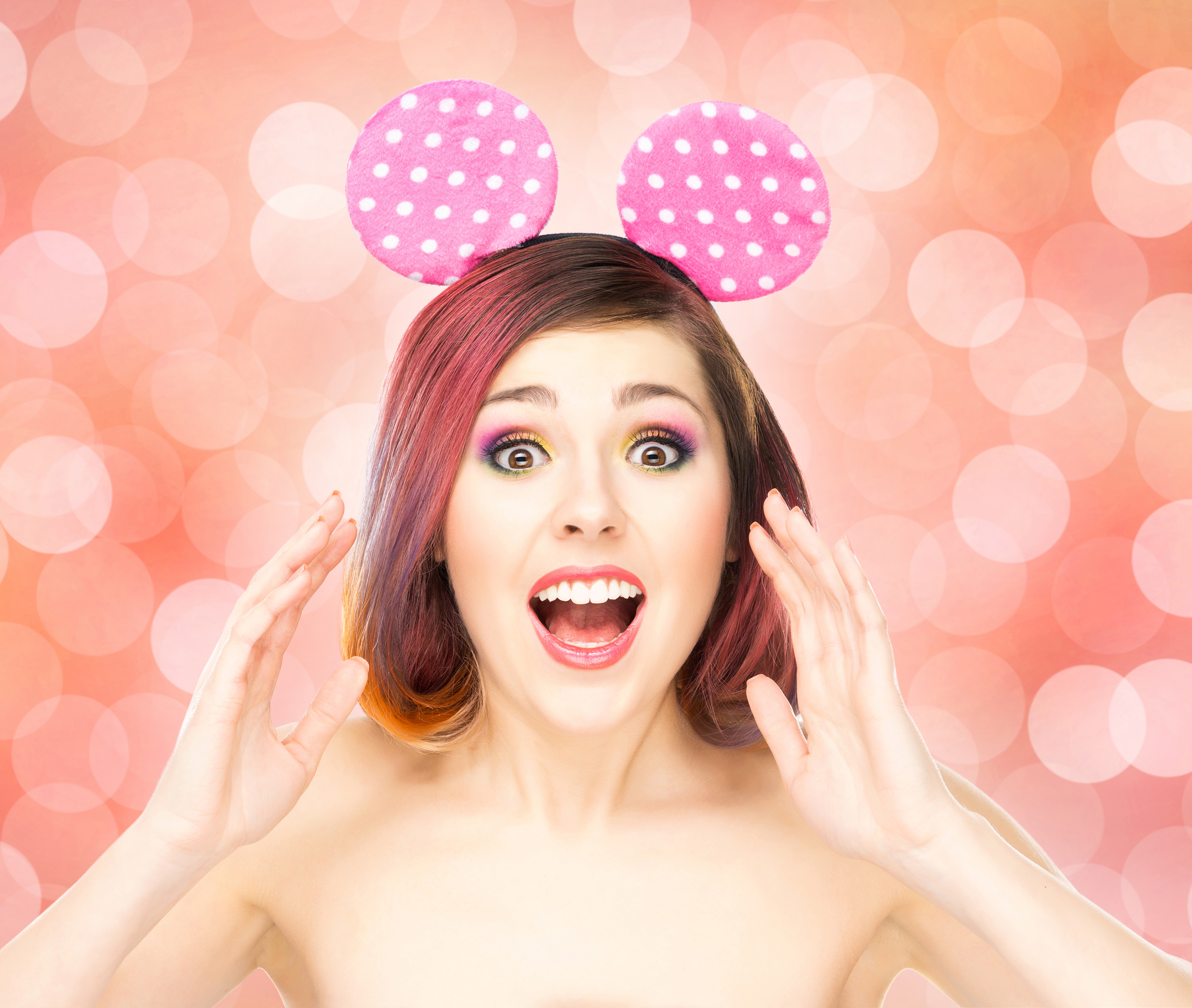 Beautiful young smiling woman in Mickey Mouse ears on bubble background.