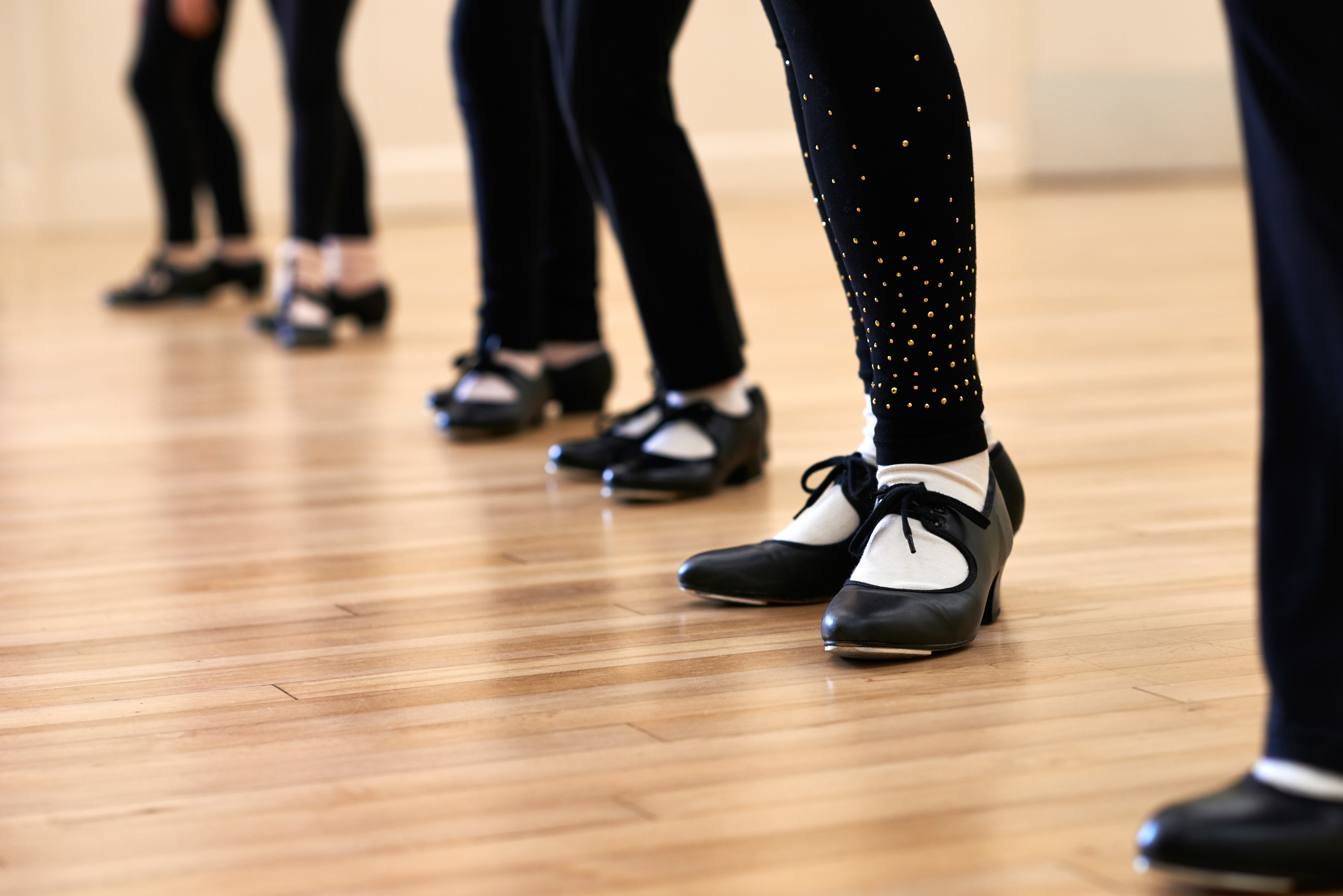 image of legs and feet of tap dancers in tap shoes on a wooden floor